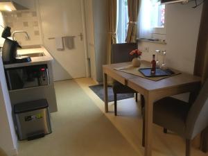 a small kitchen with a wooden table and a small kitchen with a stove at B & B Rosamie in Vlissingen