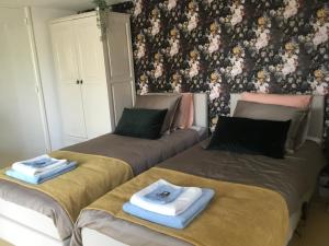two beds in a room with floral wallpaper at B & B Rosamie in Vlissingen