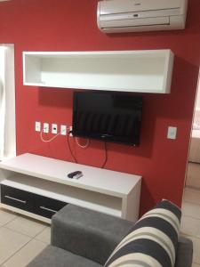 熱河市的住宿－Águas da Serra Apart Service 728A，一间客厅,在红色的墙上配有电视