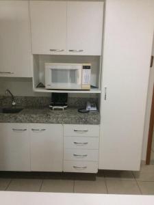 uma cozinha com armários brancos e um micro-ondas em Águas da Serra Apart Service 728A em Rio Quente