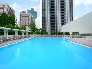 a large pool with chairs and buildings in the background at ANA InterContinental Tokyo by IHG in Tokyo