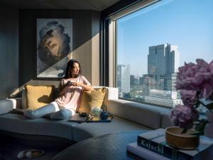 a woman sitting on a couch in a room with a window at ANA InterContinental Tokyo, an IHG Hotel in Tokyo