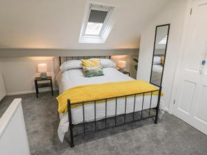 een slaapkamer met een bed met een gele deken en een spiegel bij Laridae in Whitby