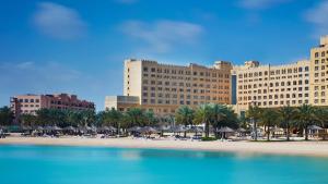 a beach with a large building and palm trees at InterContinental Doha Beach & Spa, an IHG Hotel in Doha