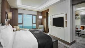 een slaapkamer met een groot bed en een televisie bij InterContinental Doha Beach & Spa by IHG in Doha
