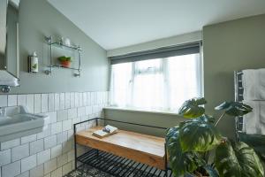 a bathroom with a window and a wooden bench at The Swan Inn in Winscombe