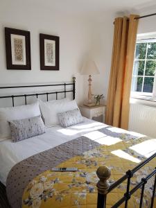een slaapkamer met een groot bed met een gele en blauwe deken bij Wisteria Haze in Cranfield