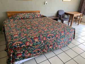 a bed with a colorful blanket on it in a bedroom at Budget Inn Motel in Austin