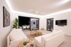 sala de estar con muebles blancos y TV en Ionian Trilogy Luxury Villas en Sami