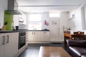 a kitchen with white cabinets and a table and a couch at H.V Apartments in Sheffield