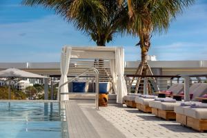 a pool with chaise lounge chairs next to a swimming pool at Kimpton - Hotel Palomar South Beach, an IHG Hotel in Miami Beach