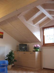 ein Wohnzimmer mit einem Dachboden, einem TV und einem Fenster in der Unterkunft Casa Rondine in Molveno
