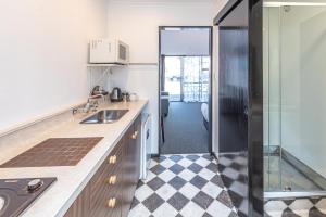 a kitchen with a sink and a glass door at Burwood Motel in Whanganui