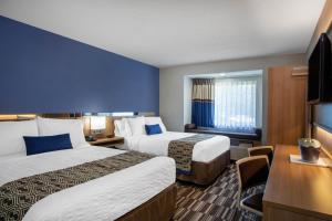 a hotel room with two beds and a desk at Microtel Inn & Suites by Wyndham Burlington in Burlington +12 photos