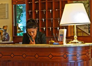 a woman sitting at a bar looking at her cell phone at Hotel Parco delle Cale in Puntone di Scarlino