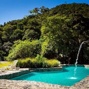 a swimming pool with a fountain and a chair at Pousada Vila Santa Barbara in São Francisco Xavier