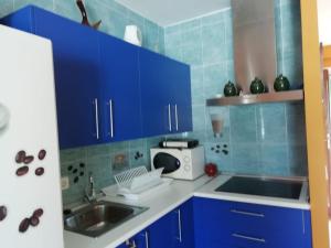 eine Küche mit blauen Schränken, einer Spüle und einer Mikrowelle in der Unterkunft El Sol de Las Negras con vistas al mar in Las Negras