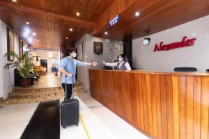 un hombre con una maleta delante de un bar en Hotel Alexander en Trujillo