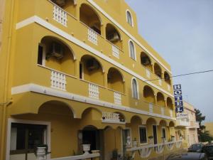 un edificio amarillo con coches estacionados fuera de él en Hotel Le Pelagie en Lampedusa
