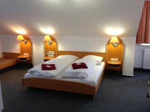 a bedroom with a bed with two red pillows on it at Hotel & Restaurant Jägerstuben in Ritterhude