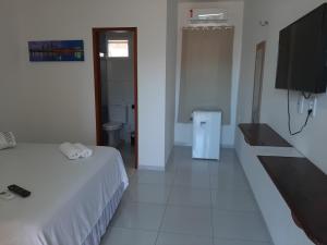 a bedroom with a bed and a tv and a bathroom at Barcelona Beach Residence in Canoa Quebrada