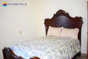 een bed met een houten hoofdeinde en witte kussens bij Casa Diamante in Puerto Peñasco