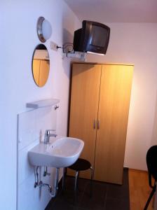 a bathroom with a sink and a tv on the wall at Hotel & Restaurant Jägerstuben in Ritterhude