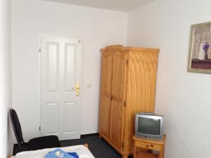 a room with a small television and a wooden cabinet at Hotel & Restaurant Jägerstuben in Ritterhude
