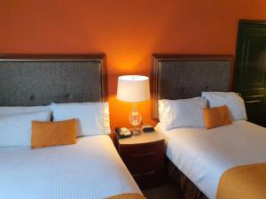Hotel San Francisco Leon في ليون: سريرين في غرفة الفندق بجدران برتقالية