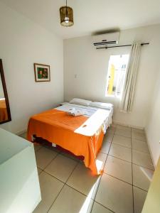 a bedroom with a bed with an orange blanket at Pousada Bem Me Quer in Ilhéus