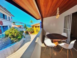 a balcony with a wooden table and white chairs at Pousada Primeira Praia Suítes in Morro de São Paulo