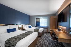 a hotel room with two beds and a flat screen tv at Microtel Inn & Suites by Wyndham Burlington in Burlington