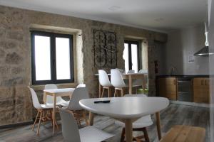uma cozinha com mesas e cadeiras brancas e janelas em ALOJAMENTO GIRASSOL - Guest House - Quarto com casa de banho privativa em Castelo Branco