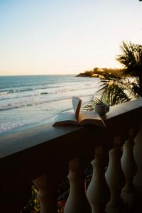 an open book sitting on a ledge next to the beach at Vista Las Olas Resort in El Cuco