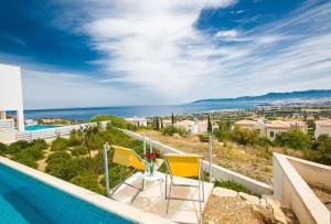 una piscina con due sedie e vista sull'oceano di Villa Tavrou Dyo - Luxury 3 Bedroom Latchi Villa with Private Pool - Stunning Sea Views a Neo Chorio