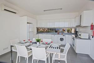 una cucina bianca con tavolo e sedie bianche di Villa Tavrou Dyo - Luxury 3 Bedroom Latchi Villa with Private Pool - Stunning Sea Views a Neo Chorio