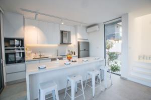 een witte keuken met een aanrecht en krukken. bij Villa Limni Enas - Luxury and Contemporary 3 Bedroom Kapparis Villa with Sea views in Paralimni