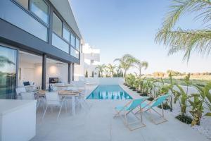 een patio met een tafel en stoelen en een zwembad bij Villa Limni Enas - Luxury and Contemporary 3 Bedroom Kapparis Villa with Sea views in Paralimni
