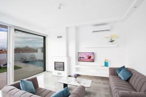 ein Wohnzimmer mit 2 Sofas und einem großen Fenster in der Unterkunft Villa Olive Gold Luxury and Brand New 2BDR Protaras Villa with Private Pool in Protaras