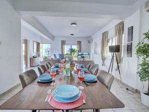 a dining room with a long wooden table and chairs at Villa Oforo Selene - Stunning 4 Bedroom Villa - By Fig Tree Bay Beach - Sea Views in Protaras
