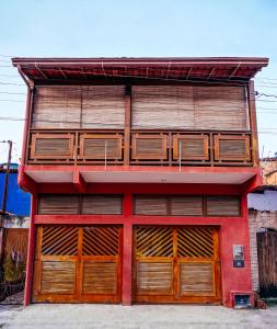 un edificio rojo con puertas y ventanas de madera en Surf Red House - 3 quartos c ar - 50m da Rua Principal, en Itacaré