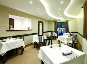 ein Restaurant mit weißen Tischen und Stühlen in einem Raum in der Unterkunft Garni Hotel Vozarev in Belgrad
