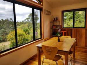 a dining room with a table and two windows at Southern Forest Accommodation in Southport