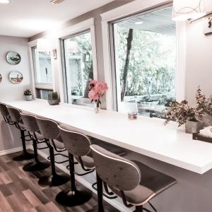 a kitchen with a large white counter and chairs at Along River Ridge in Calgary