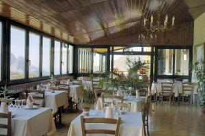 a restaurant with white tables and chairs and windows at Hôtel Aïtone in Evisa