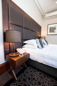 a bedroom with a bed and a table with a lamp at Avonmore On The Park Boutique Hotel in Sydney