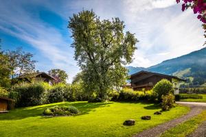 zielony dziedziniec z drzewem i domem w obiekcie Chalet Matzhof w mieście Leogang