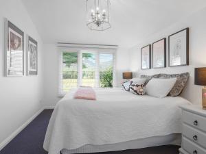 a white bedroom with a large bed and a window at Meerea Country Estate adjoining Wollombi National Park in Bulga