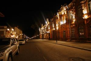 een stadsstraat 's nachts met auto's geparkeerd voor gebouwen bij Hotel Na starom meste in Biejsk