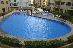 una gran piscina con sillas y gente en un edificio en Gulf Suites Hotel Amwaj en Manama